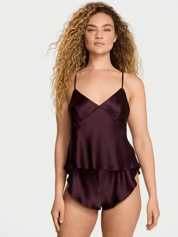 Front view of a woman wearing Victoria's Secret Winter Wine satin cami and shorts set on a light grey background.
